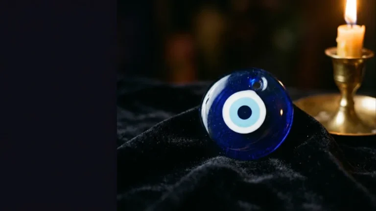 Blue nazar evil eye bead on black velvet beside a candle, illustrating the signs of evil eye