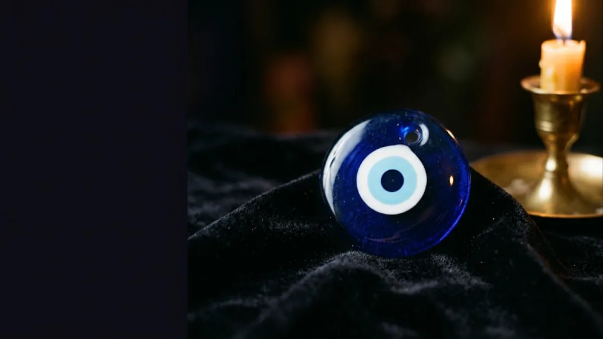Blue nazar evil eye bead on black velvet beside a candle, illustrating the signs of evil eye